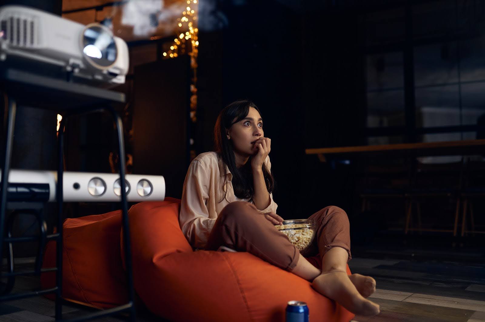 Teen girl sitting on beanbag chair bites her nails in anticipation while watching movie | 7 Movies Like Parasite